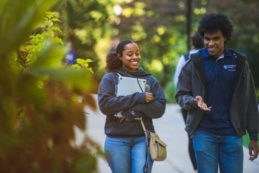 Two students having a conversation while walking on campus
