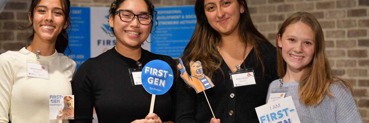 Four students smile at camera while holding #PSUFirstGen signs