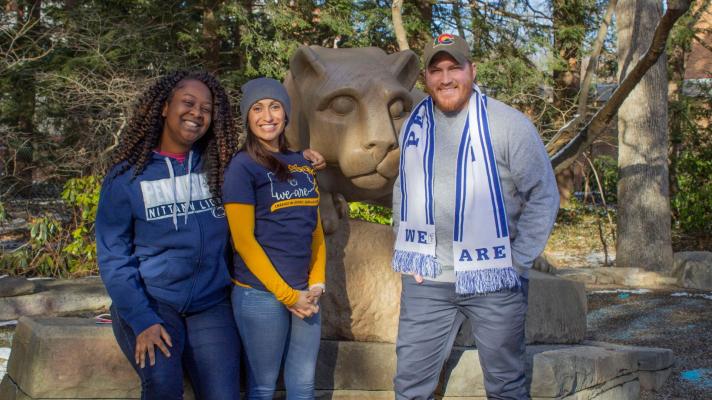 Three adult students standing at the lion shrine