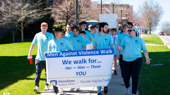 Male students walking carrying a banner