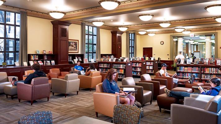 Students sitting in library surrounded by books